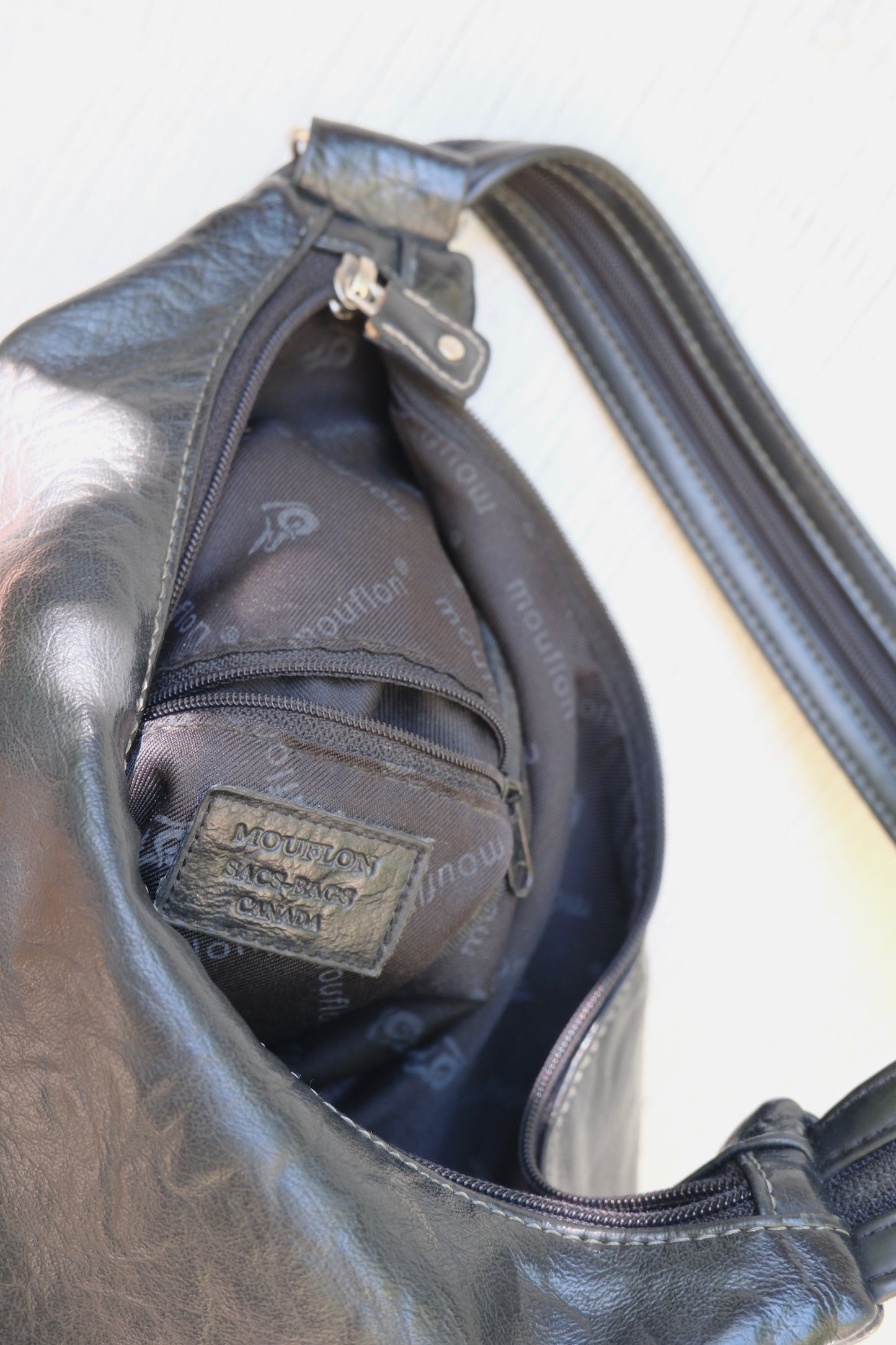 Black faux leather bag with a visible Mouflon brand logo on a white background