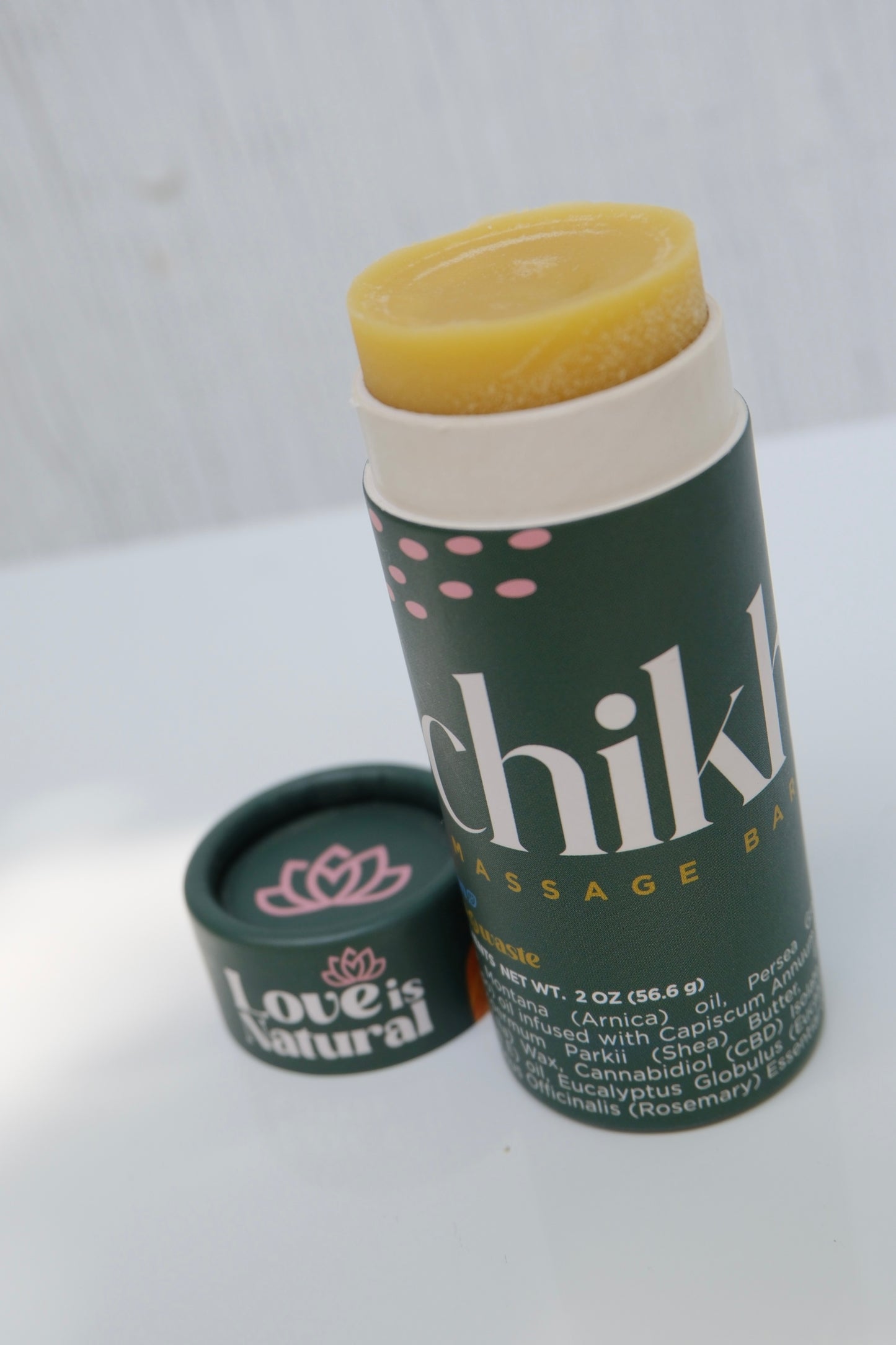 Green cylinder massage stick with cap off and 'Chikhuya' branding on a light wooden surface.