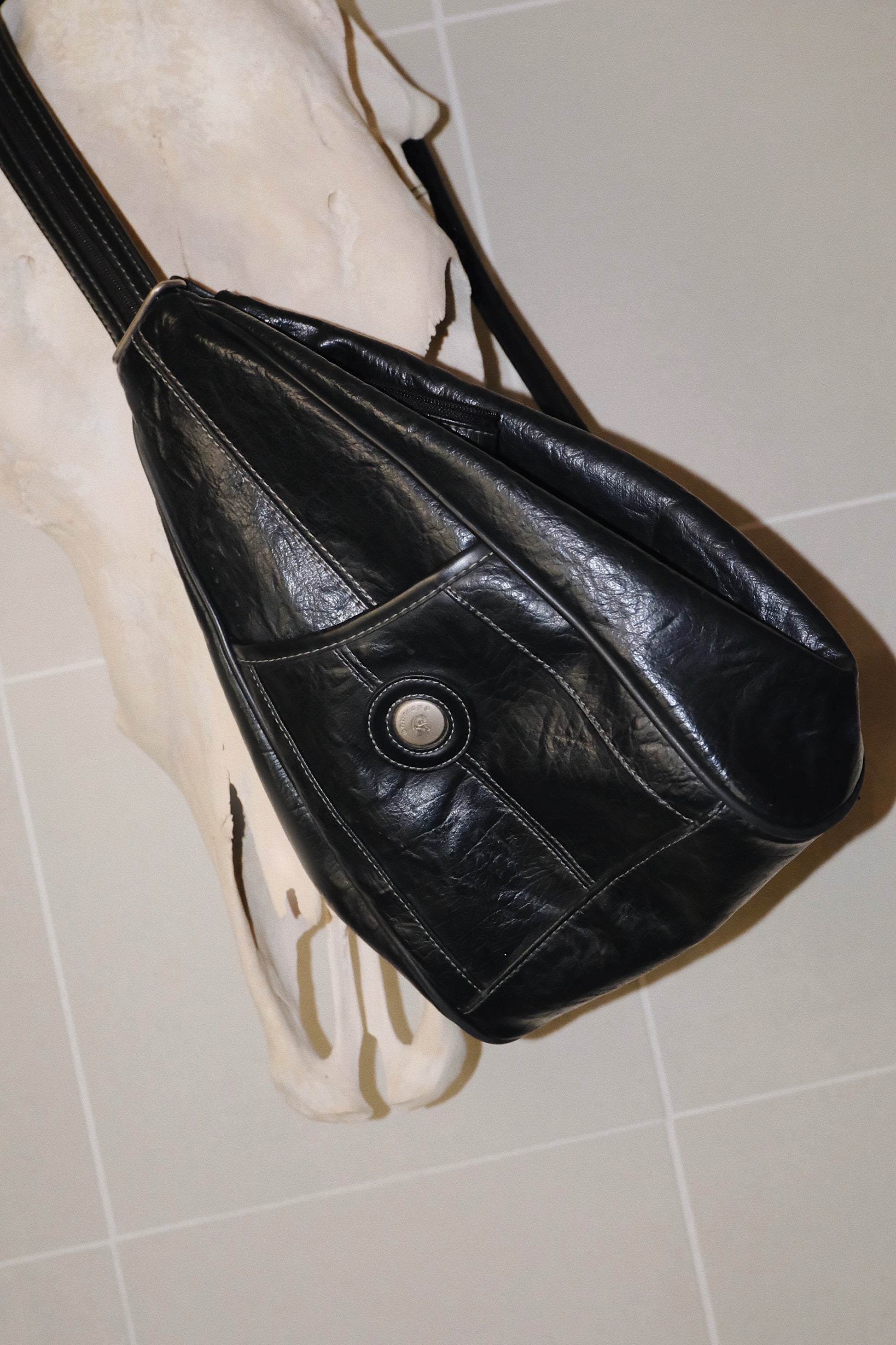 Black faux leather bag on a white tiled background