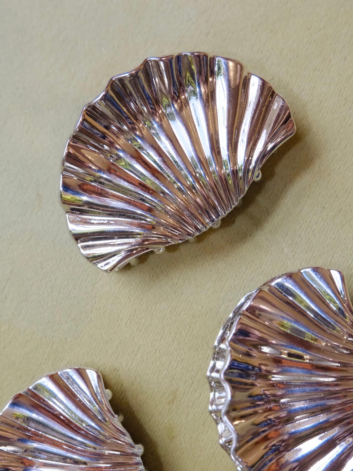 Silver shell-shaped hair clips on a light green background