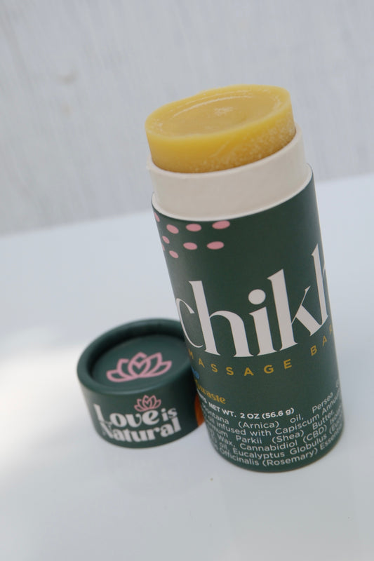 Green cylinder massage stick with cap off and 'Chikhuya' branding on a light wooden surface.