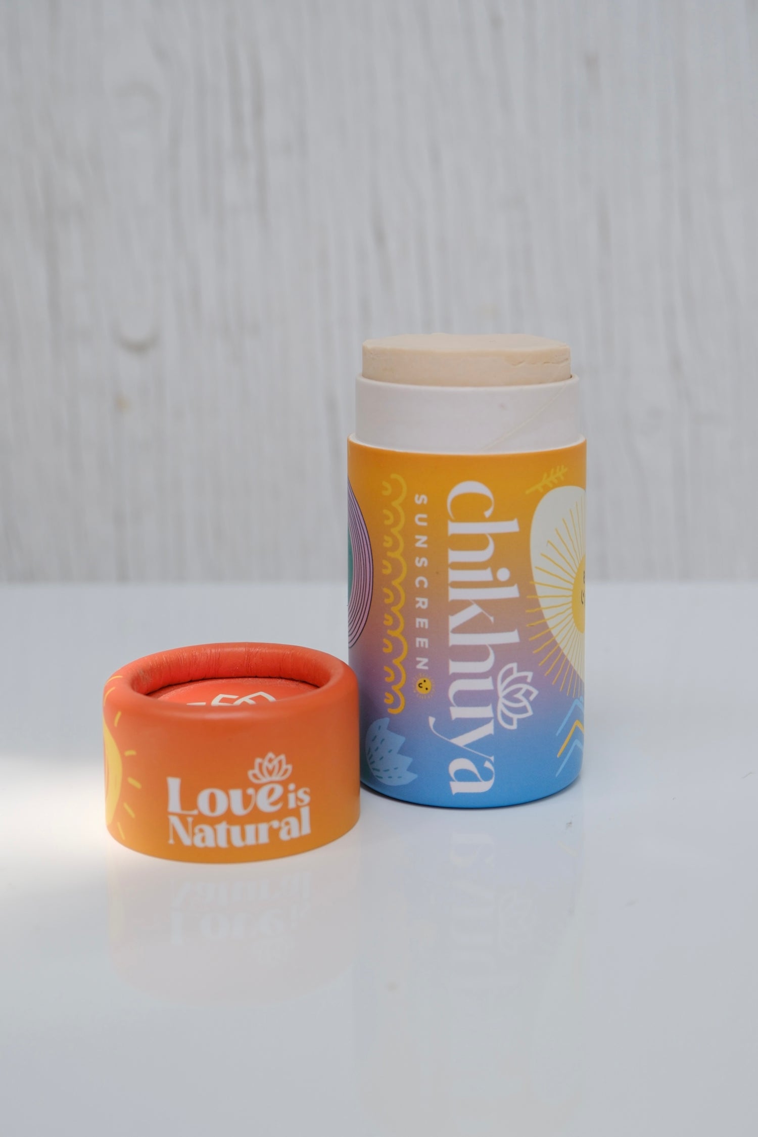 Cylinder stick of sunscreen with cap off and 'Chikhuya' colourful branding on a light gray background